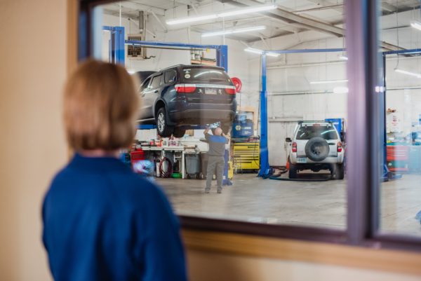 Photo of Female Customer Looking at Her Jeep on a Lift at McCormick Automotive Center in Fort Collins, Colorado