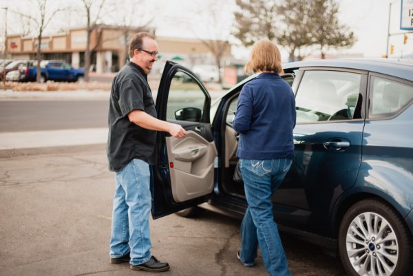 Photo of Corry, owner of McCormick Automotive Center, helping female customer into her vehicle after a repair