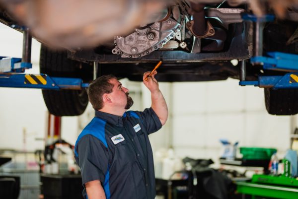 Photo of Mechanic Looking at Underside of Car on Lift and Performing Repair at McCormick Automotive Center in Fort Collins, Colorado