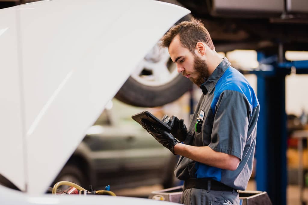 Photo of Auto Mechanic Reviewing Tablet While Conducting Maintenance at McCormick Automotive Center in Fort Collins, Colorado