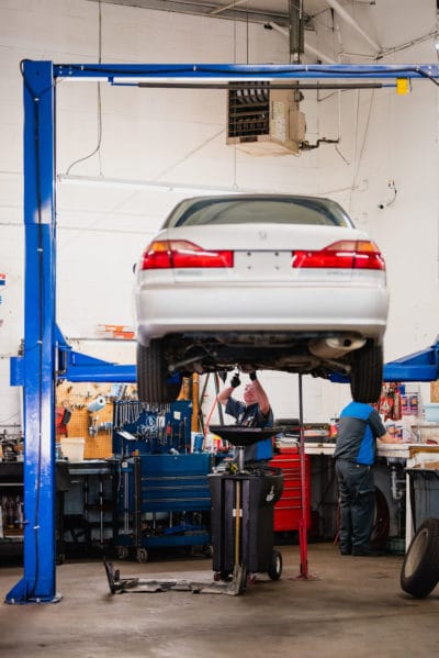 Mechanic Looking at Underside of Car on Lift at McCormick Automotive Center in Fort Collins, Colorado