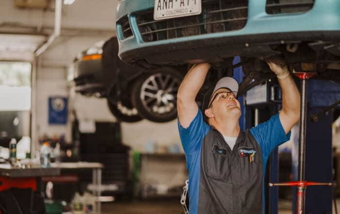 Photo of mechanic at McCormick Automotive Center inspecting underside of vehicle on a lift